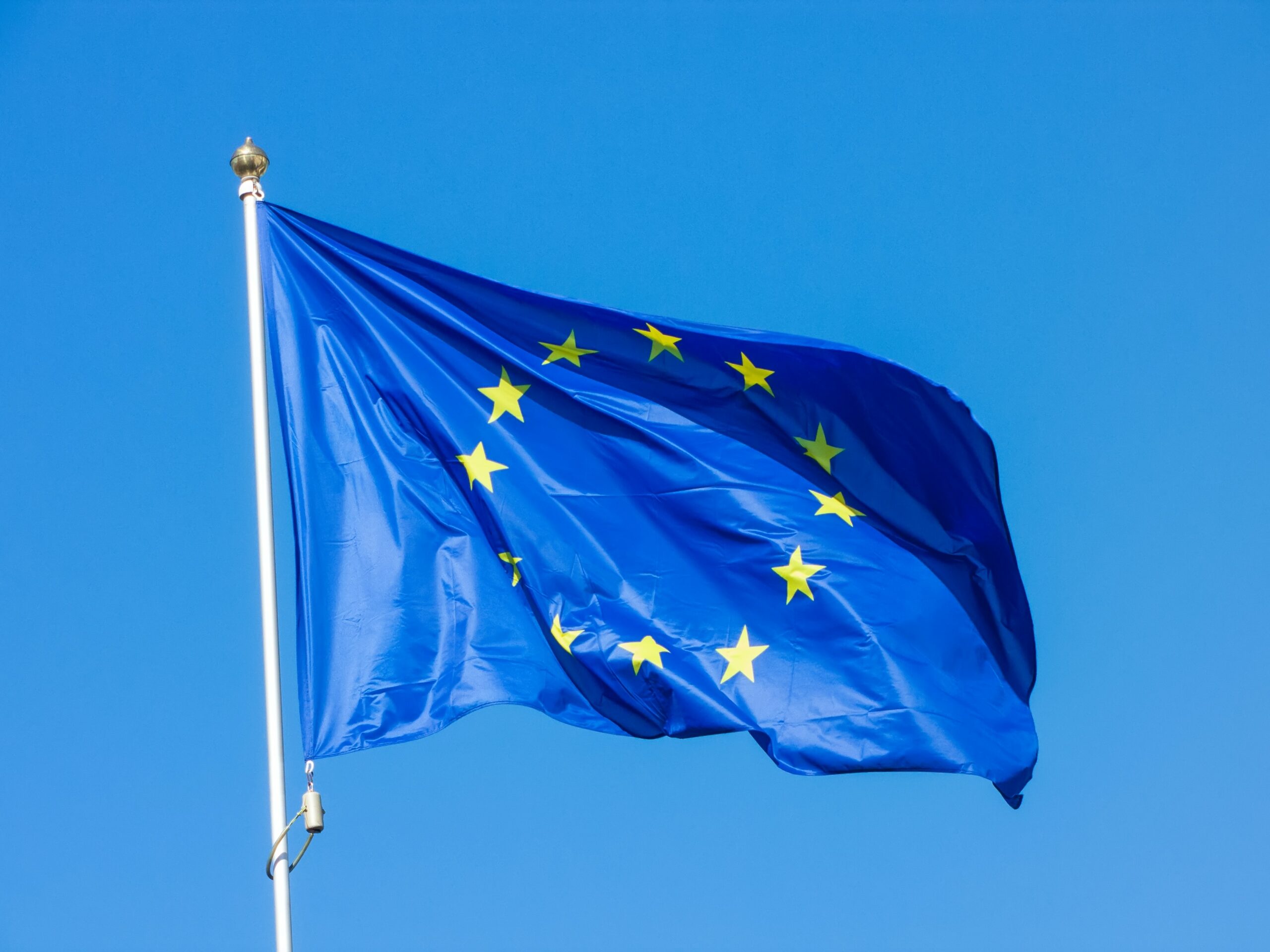 Dekoratives Symbolfoto zeigt eine euroäische Flagge im Wind vor blauem Himmel.